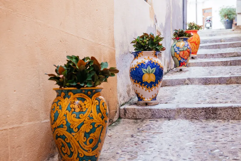 Cefalù old-town alley with Sicilian ceramic pots on the steps