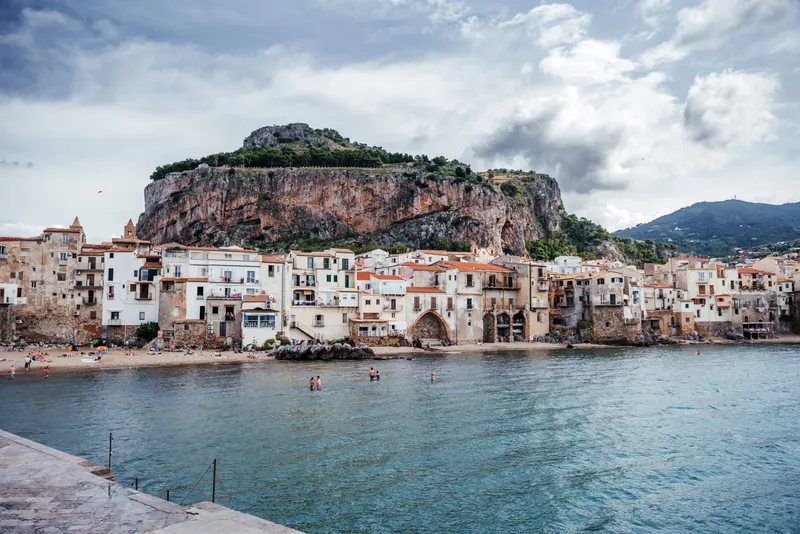 The classic Cefalù panorama — fishermen's houses, cathedral towers and La Rocca from the old harbour