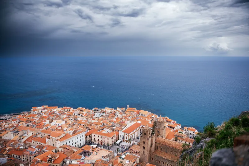 Cefalù's terracotta rooftops and the sea under a dramatic Sicilian sky
