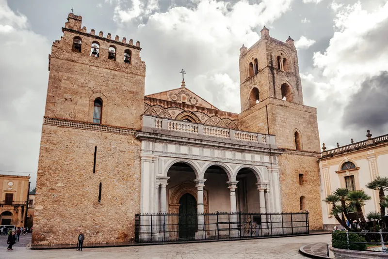 The stone facade of Monreale Cathedral with its two Norman towers and the 16th-century Renaissance portico across the front