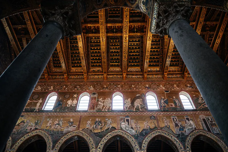 Looking up in Monreale Cathedral at the painted and gilded open-timber ceiling above the clerestory windows and mosaic nave walls